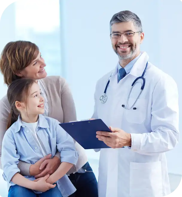 A smiling doctor and his family hold a clipboard in an emergency room setting, conveying a sense of joy and support.